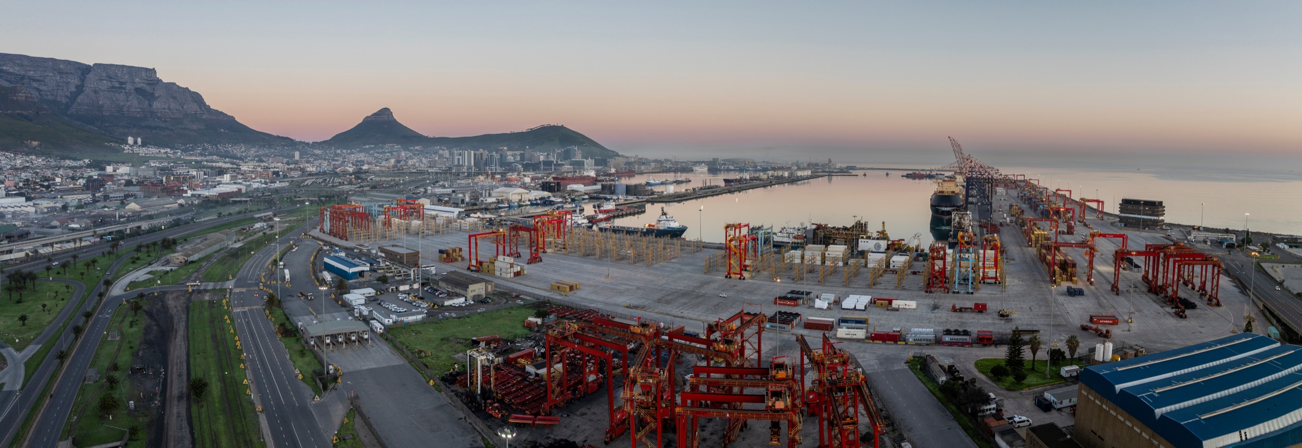 Cape Town harbour infrastructure beneath Table Mountain at sunset